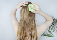 Solid Hair Shampoo. Close-up Of A Blonde Girl In The Bathroom, Which Lathers Her Hair With Dry Shampoo. Lots Of Foam And Peek Effect.