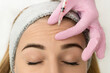 Close-up of the hands of an expert cosmetologist injecting botox into a woman's forehead. Correction of forehead and eye wrinkles with botulinum toxin