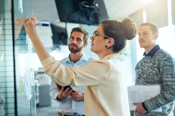 Poster - Everything becomes clearer once you puzzle through it. Shot of a group of businesspeople brainstorming with notes on a glass wall in an office.