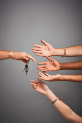 Canvas Print - Who wants to drive. Studio shot of unidentifiable hands reaching for a set of keys against a gray background.