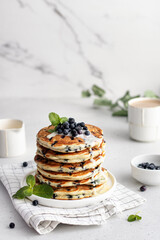 Stack of pancakes with fresh blueberries topping on marble. Delicious homemade breakfast.