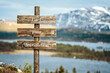 © Jon Anders Wiken - find your destination text quote written on wooden signpost outdoors in nature with lake and mountain scenery in the background. Moody feeling.