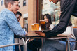 © Samuel Perales - waiter serving drinks at a table of friends of different ethnic backgrounds