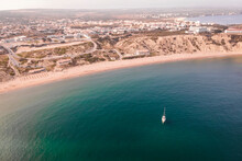 Aerial View Of A Sailing Boat In The Ocean Near The Coastline In Sagres, Algarve Region, Portugal.