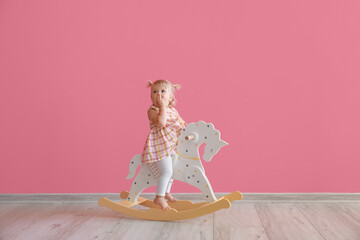 Sticker - Adorable baby girl with rocking horse near pink wall