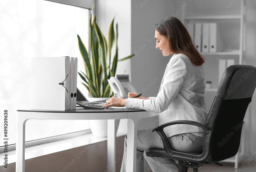 Pretty businesswoman working at table in office