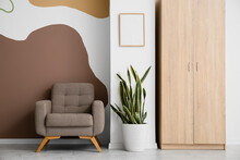 Armchair, Houseplant And Cabinet Near Color Wall