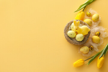 Nest with painted Easter eggs, tulip flowers and bunny on yellow background