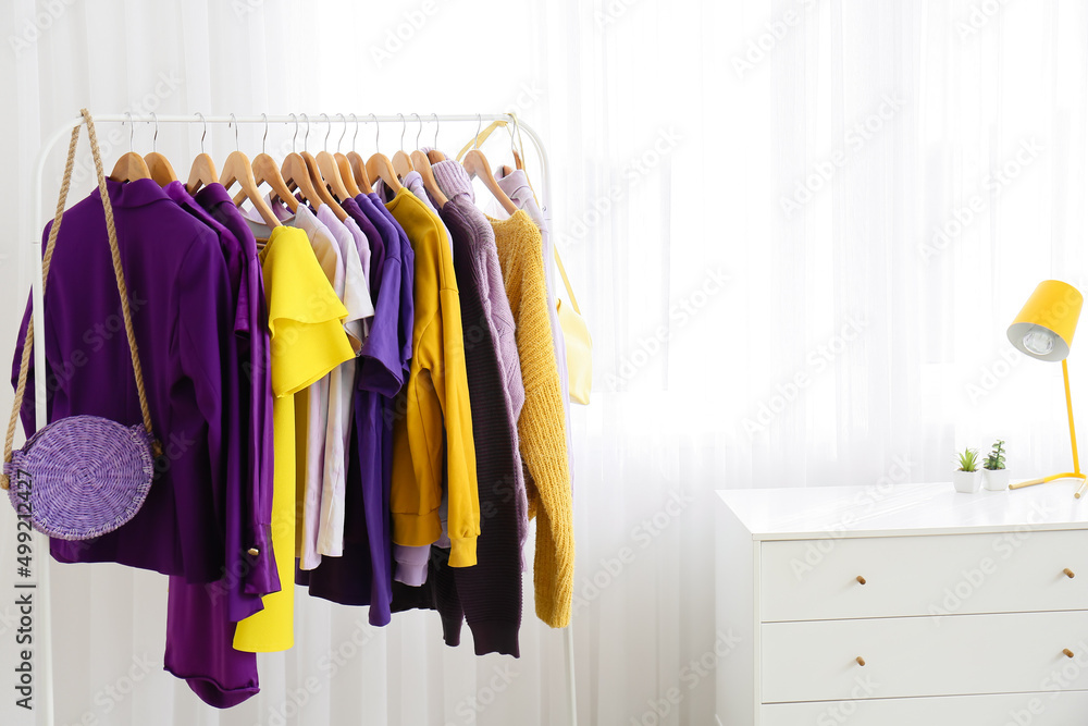 Rack with clothes and bag near light curtain in dressing room