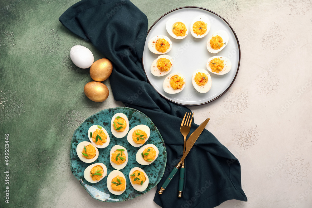 Plates with stuffed eggs, cutlery and napkin on grunge background. Easter celebration