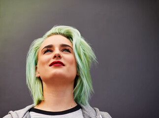 On top of the latest hair trends. Shot of a trendy young woman with mint green hair posing against a gray background.