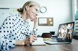 © Alex from the Rock - Smiling woman with googles has video call conference with her remote team. Laptop with camera teamwork