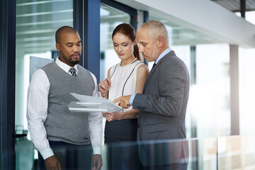Aufkleber - Going over the paperwork. Cropped shot of three businesspeople looking over paperwork in the office.