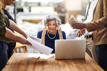 Strained by so many difficulties. Cropped shot of a stressed out businesswoman surrounded by colleagues needing help in an office.