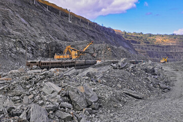 Excavator loads iron ore into wagons. Iron ore mining