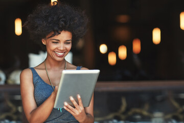 Customers have left some great reviews online about her cafe. Cropped shot of a young woman using a digital tablet in a cafe.