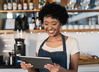 Sticker - Taking advantage of technological tools to boost sales. Shot of a young woman using a digital tablet while working in a cafe.