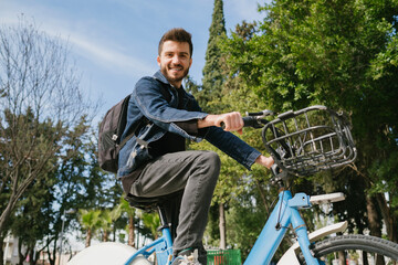 Wall Mural - Cycling trip, handsome college student with a backpack prefers a bicycle as a means of transportation to school, green transportation method and green environment