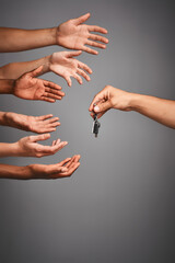 Poster - Vying for the drivers seat. Studio shot of unidentifiable hands reaching for a set of keys against a gray background.