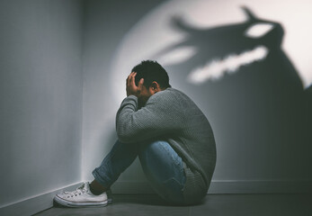 if dreams come true, can nightmares too. shot of a young man sitting in the corner of a dark room wi