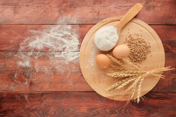 Round bread, 2 brown eggs, wheat ears, white flour in a light wooden spoon. Concept agricultural, farm natural products, ingredients for baking, harvest. Import Export.