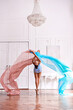 Ballerina dancing with fabrics in a white hall
