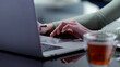 © nimito - Cropped shot of female hand scrolling touchpad on laptop sitting at desk with cup of tea