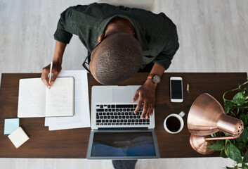 The factory is in production. Shot of a young businessman typing on his laptop while working from home.