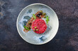 Modern style gourmet tartar raw from beef filet with capers and amarena cherry served with truffle cream and lettuce as top view on a Nordic design plate with copy space