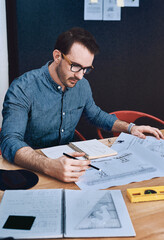 Wall Mural - Creativity at work. Cropped shot of a handsome young male architect working with blueprints in a modern office.