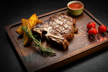 Wall Mural - T-Bone steak with sauce and potatoes, on a wooden board