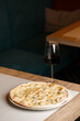 Four cheese pizza quattro formaggi with glass of wine on dark background.
