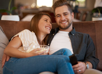 Wall Mural - Television is the most common and best form of entertainment. Cropped shot of a young couple relaxing with popcorn on the sofa at home.