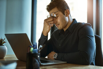 Aufkleber - When the stress of work triggers severe migraines. Shot of a young businessman looking stressed out while working on a laptop in an office.