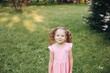 © Вячеслав Косько - A little cute baby girl in a pink dress in a green park in spring or summer.