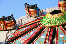 Fairground Ride. A Brightly Decorated And Illuminated American Style Waltzer Ride Raising To A Vertical Position.
