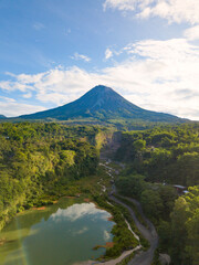 Wall Mural - photo of Natural landscape with river and Volcano emitting smoke. The river splits the cliff as lava flows. The volcano is Mount Merapi