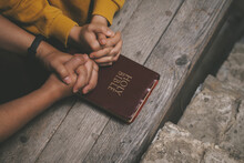 Close-up Two Christian Read Bible. Hands Folded In Prayer On A Holy Bible On Wooden Table. Online Group Worship, World Day Of Prayer, International Day Of Prayer, Hope, Gratitude, Thankful, Trust