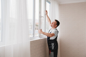 a repairman repairs, adjusts or installs metal-plastic windows in the apartment.