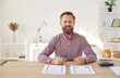 © Studio Romantic - Portrait of smiling young Caucasian businessman sit at desk at home office work with paperwork manage finances. Happy man employee or speaker talk on video call, record business webinar.