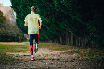 Wall Mural - A view of a runner's back warming up before running training. Sports photo with a dark place for editing or for the title