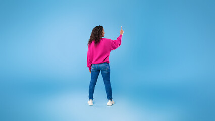 Wall Mural - Back view of millennial African American lady touching imaginary screen, pressing button, using virtual interface