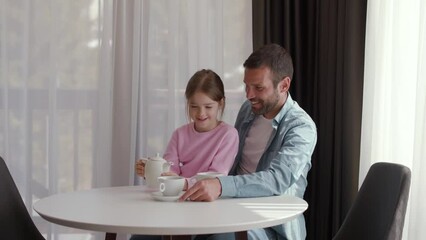 Wall Mural - Father and daughter drinking tea together at the living room