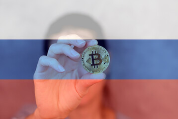 Bitcoin in a woman's hand close-up against the background of the flag of Russia. Cryptocurrency in Russia