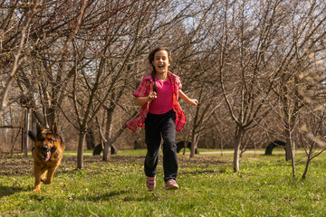 Wall Mural - little girl running fast with a shepherd in the park