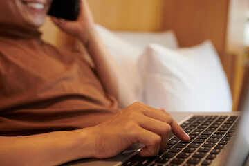 Wall Mural - Young man pushing button on laptop when talking on phone with colleague or client