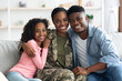 © Prostock-studio - Family portrait of happy black kid, husband and military wife