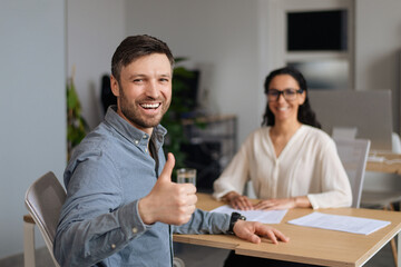 Wall Mural - Successful work interview. Happy young Caucasian guy showing thumb up gesture after speaking to hiring manager at office