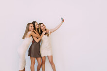Young Happy Women Friends Posing Isolated Over White Wall Background Take A Selfie By Camera On A Party.