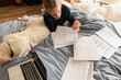 © Tetra Images - Teenage girl (16-17) lying on bed with dog and doing homework
